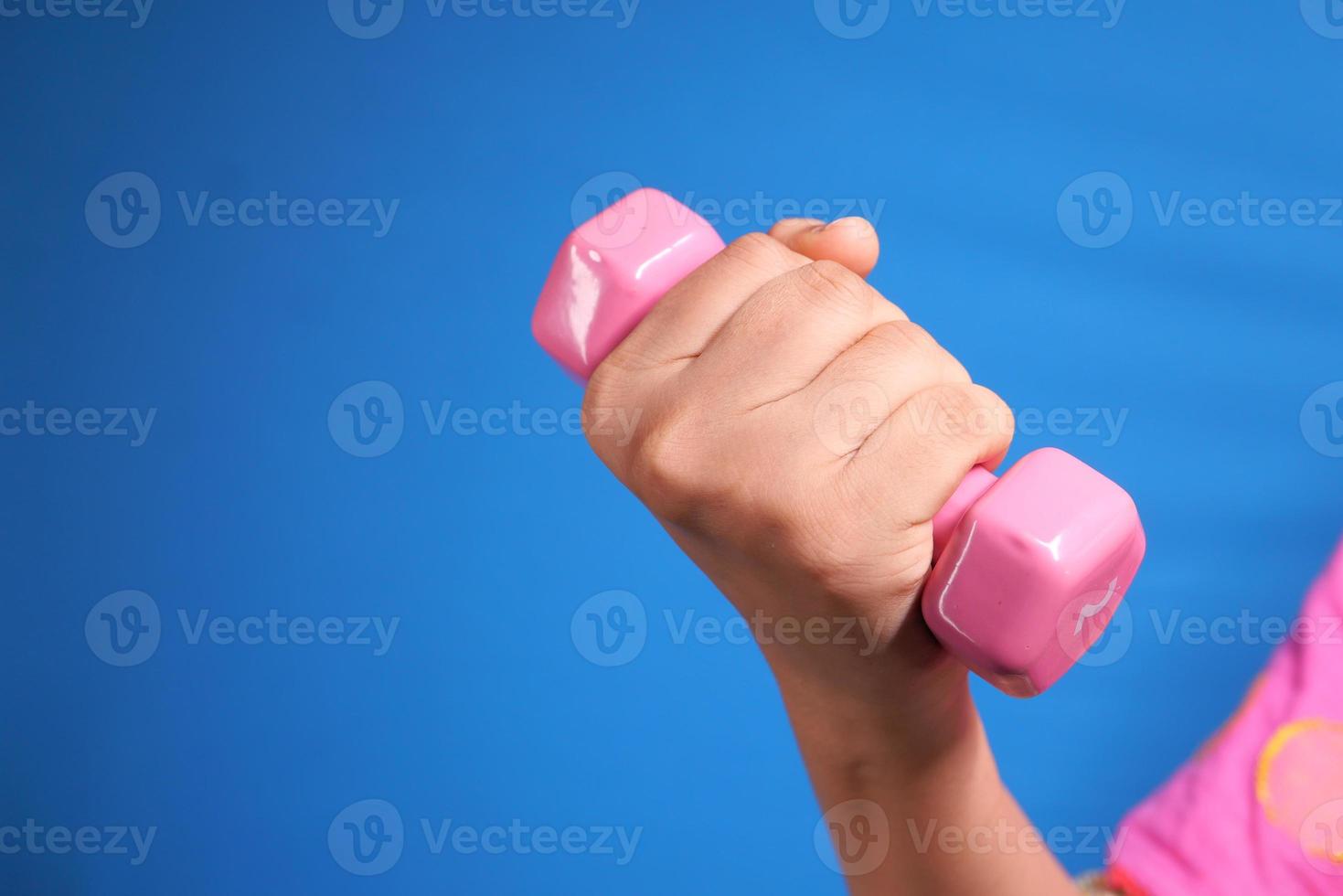 Close up of woman holding pink dumbbell on blue background photo