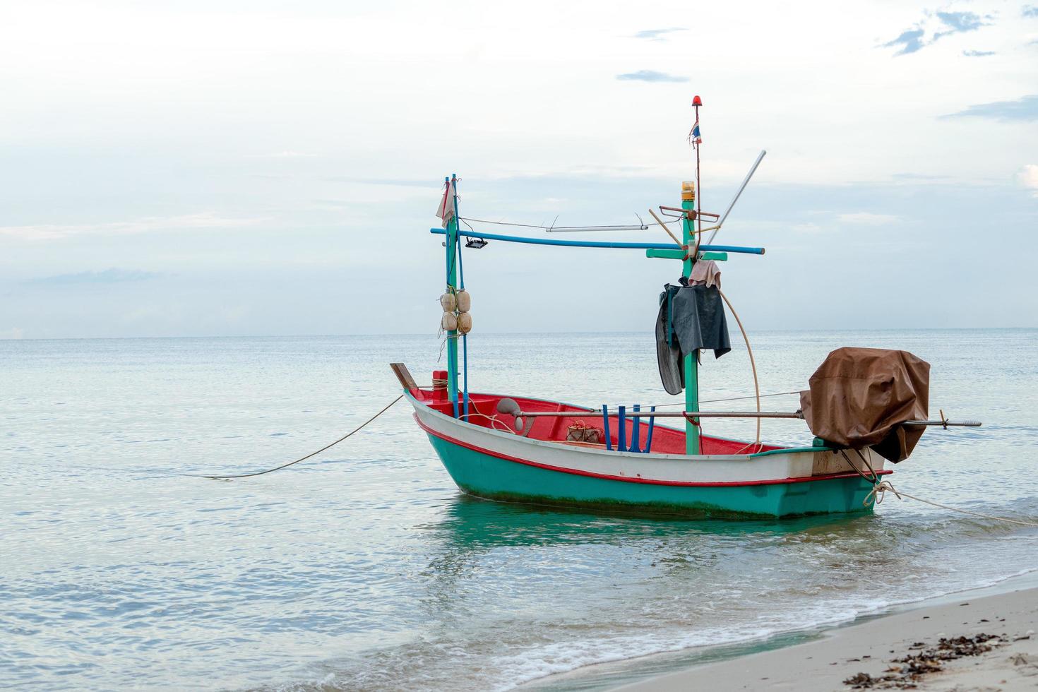 Small traditional fishing boat floating in the sea at coast with calm surface photo