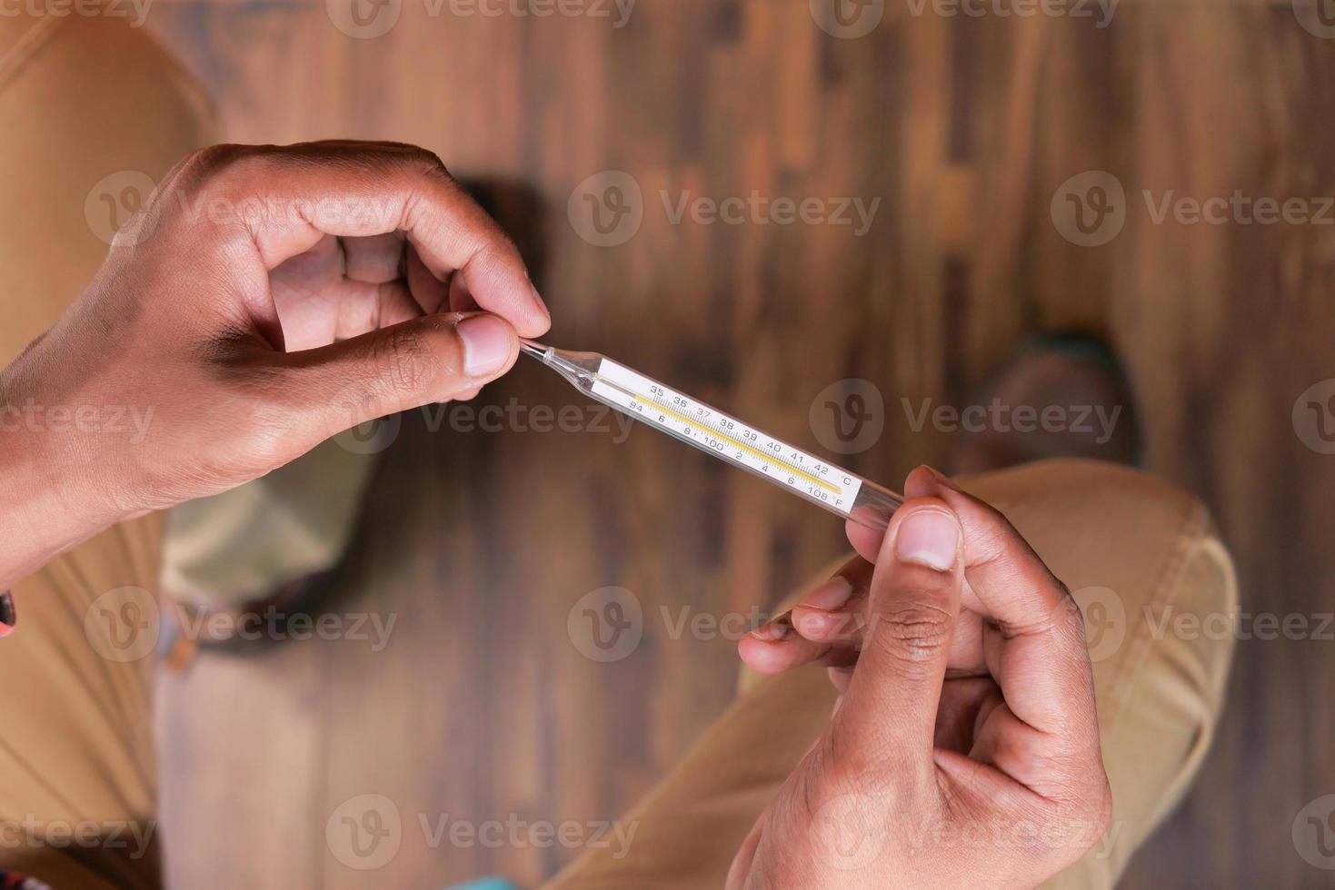 hombre sosteniendo un termómetro foto