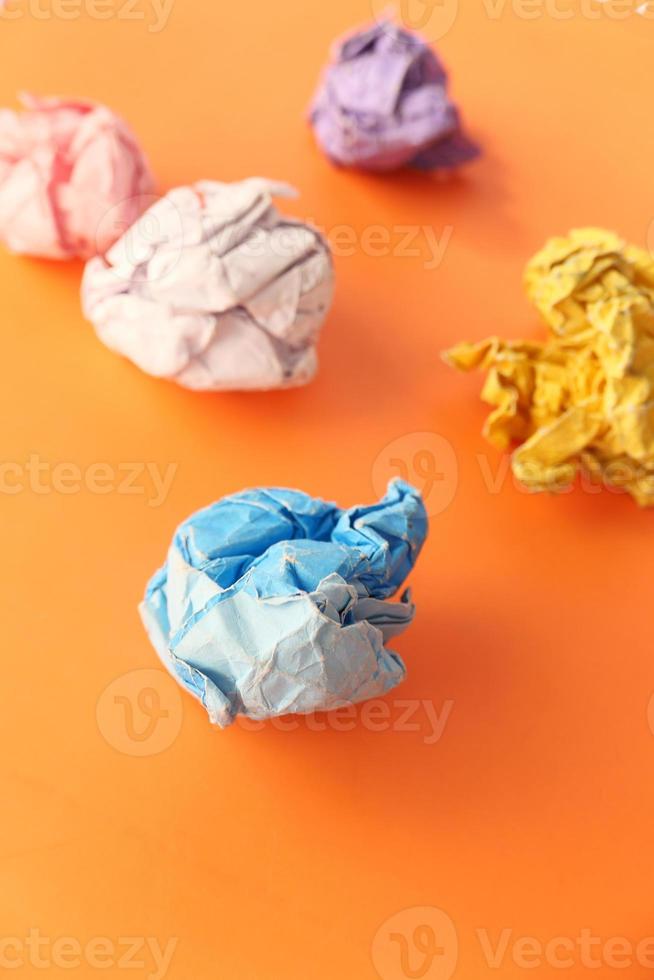 Crumbled colorful papers on orange background photo