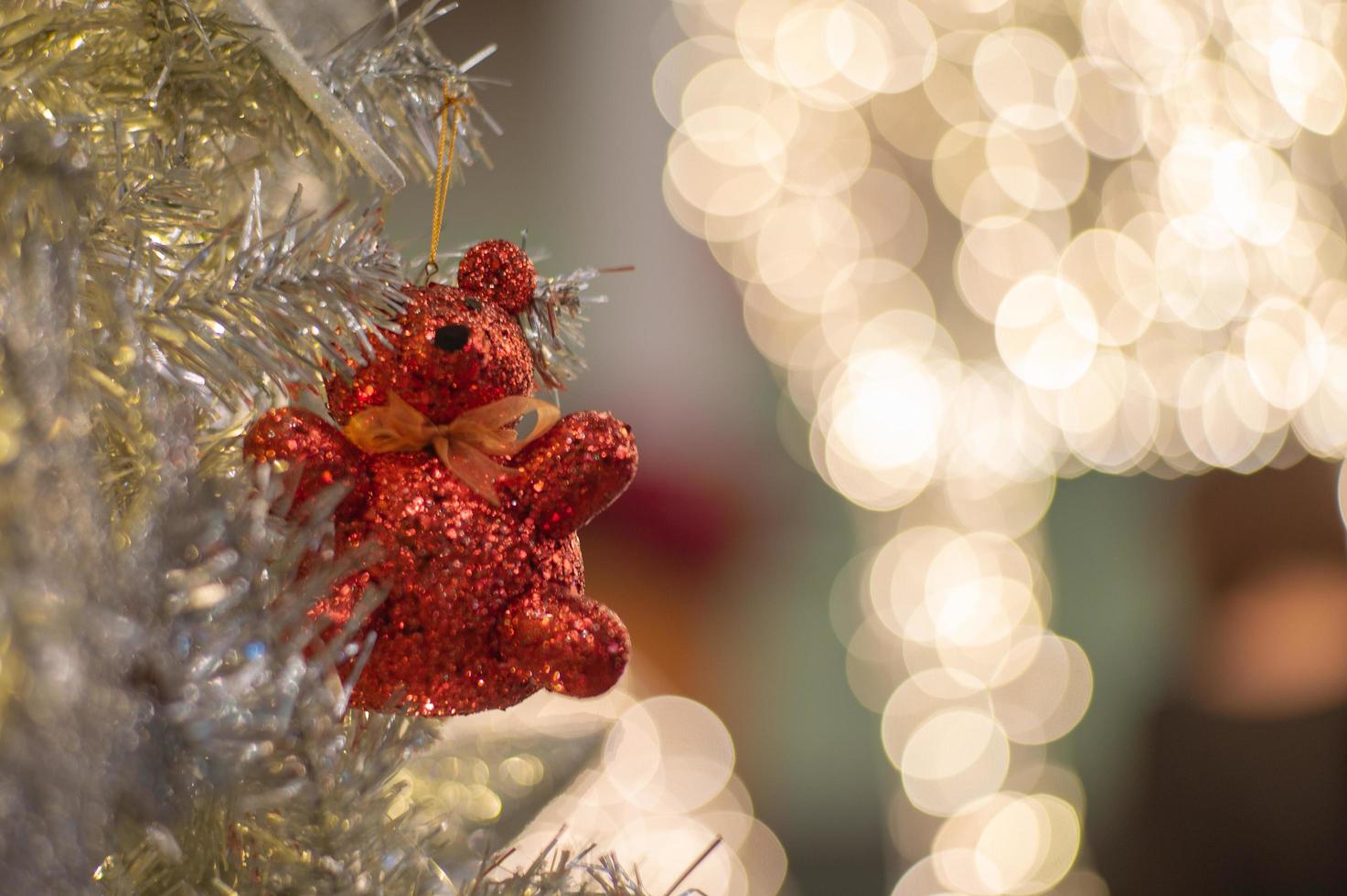 Abstract background of glittering bokeh lights with blurred ornament on the silver Christmas tree in foreground photo