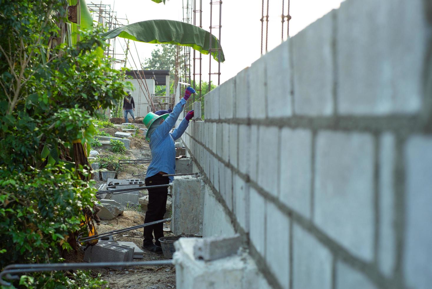 Perspective of concrete brick wall with worker installing the structure in background photo