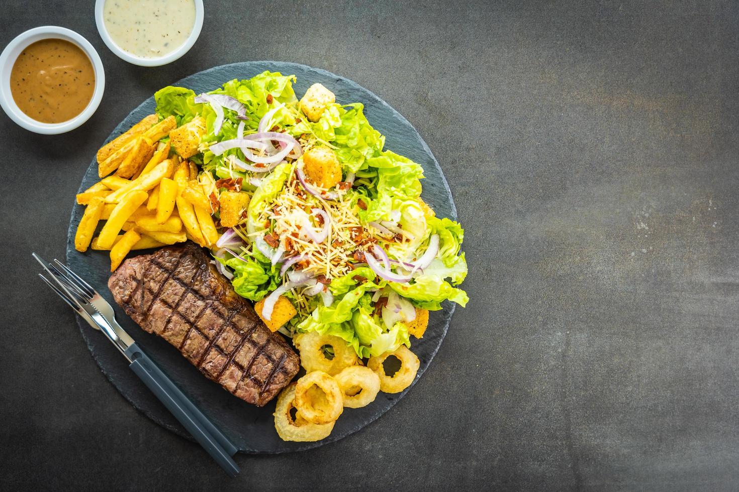 Grilled beef meat steak with french fries onion ring with sauce and fresh vegetable photo