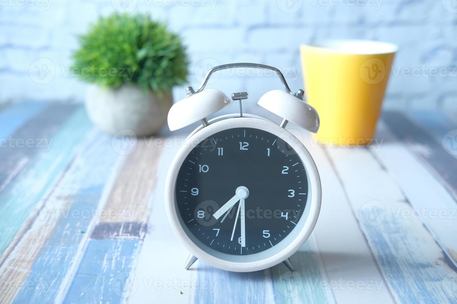 Alarm clock and yellow coffee mug on table photo