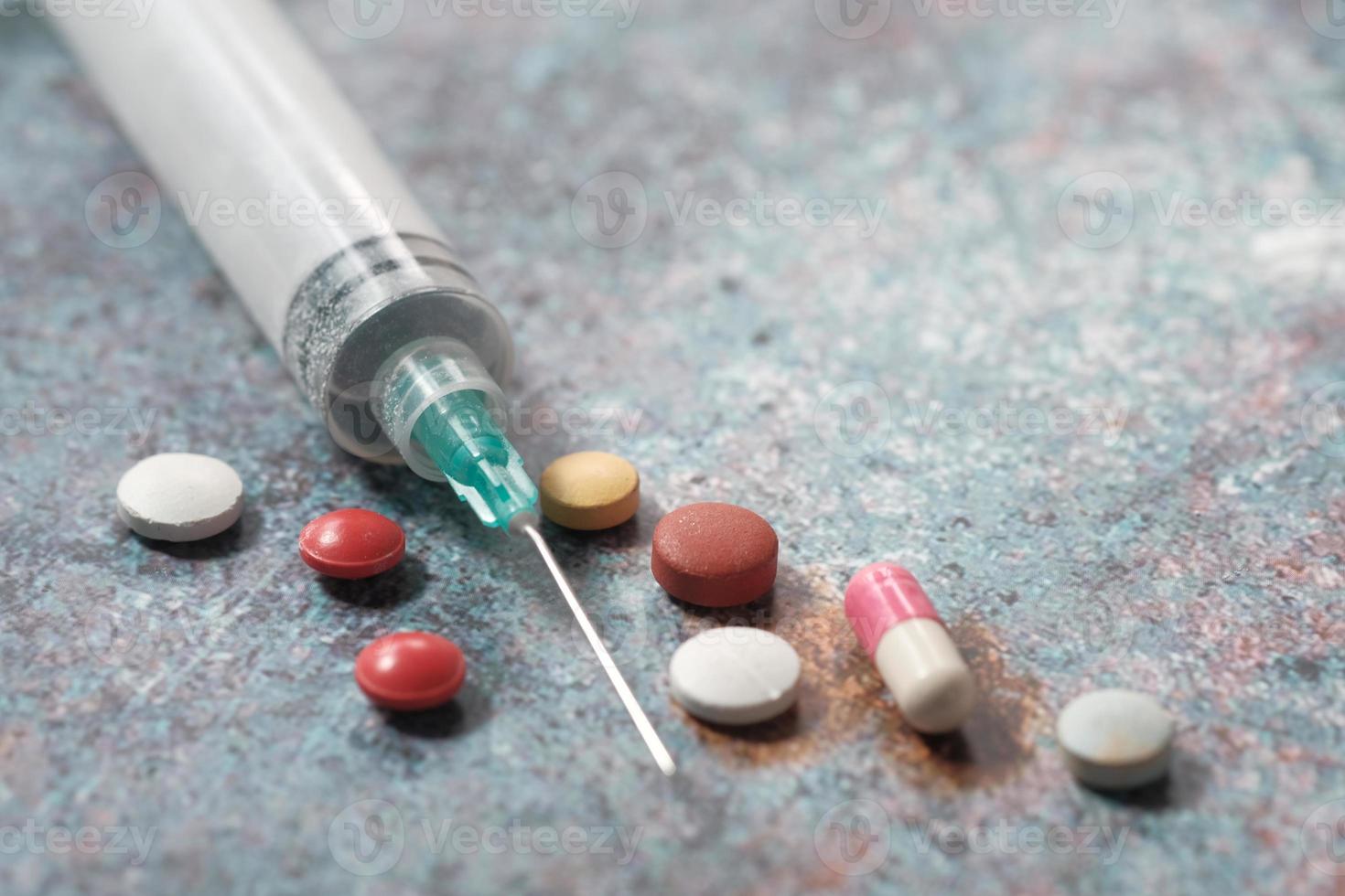 Syringe and pills close up photo