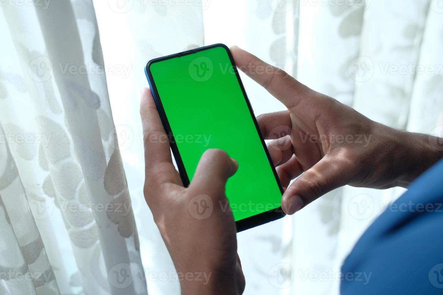 Hombre usando un teléfono inteligente con pantalla verde en el interior foto