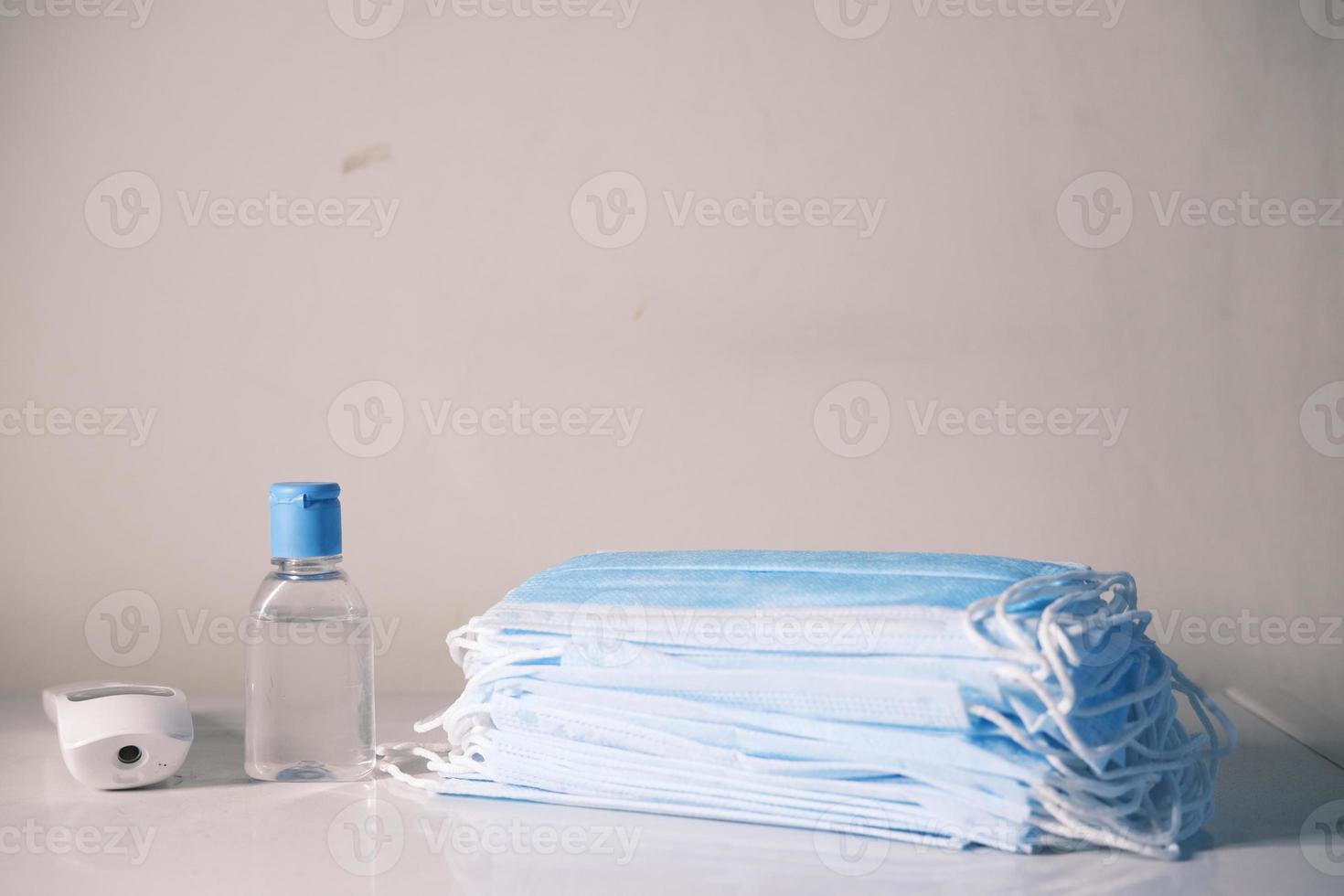 Surgical masks, thermometer, and hand sanitizer on neutral background photo