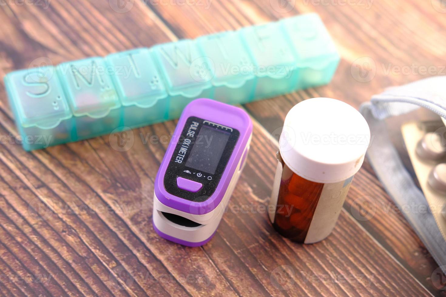 Pulse oximeter and pill container on table photo