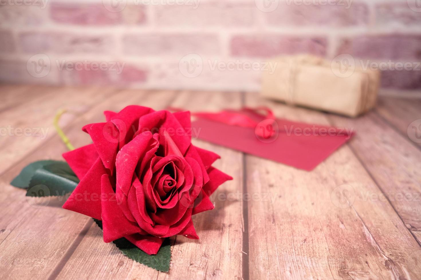 Rosa roja y regalos del día de san valentín en la mesa de madera foto