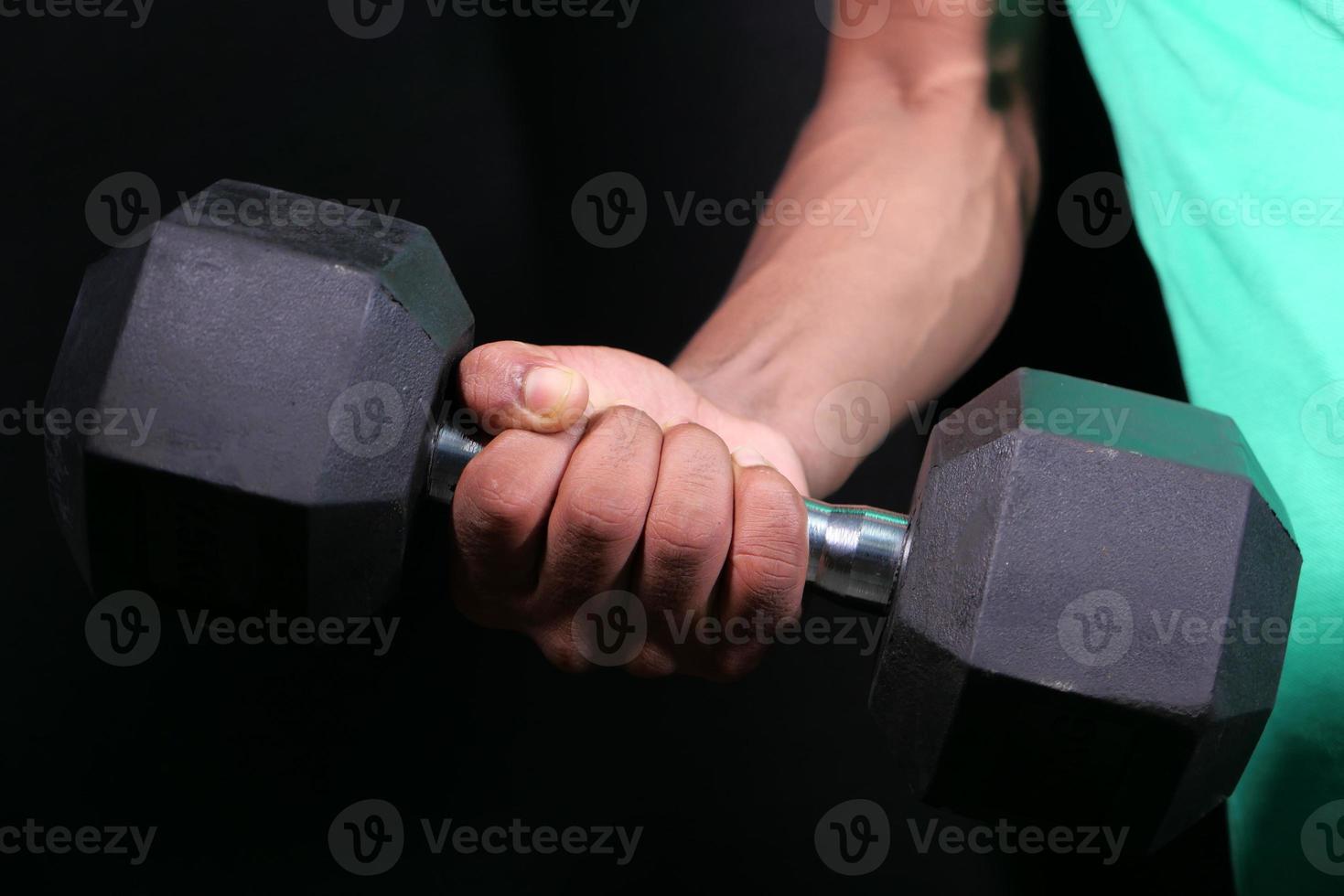 Mano de hombre joven haciendo ejercicio con pesas en el interior foto