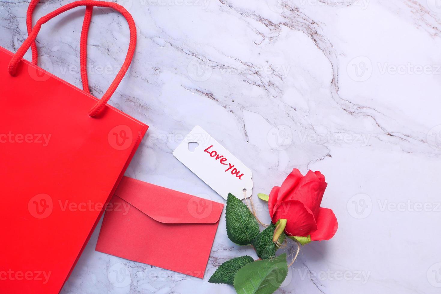 Top view of gift box, envelope, and rose flower on white background photo