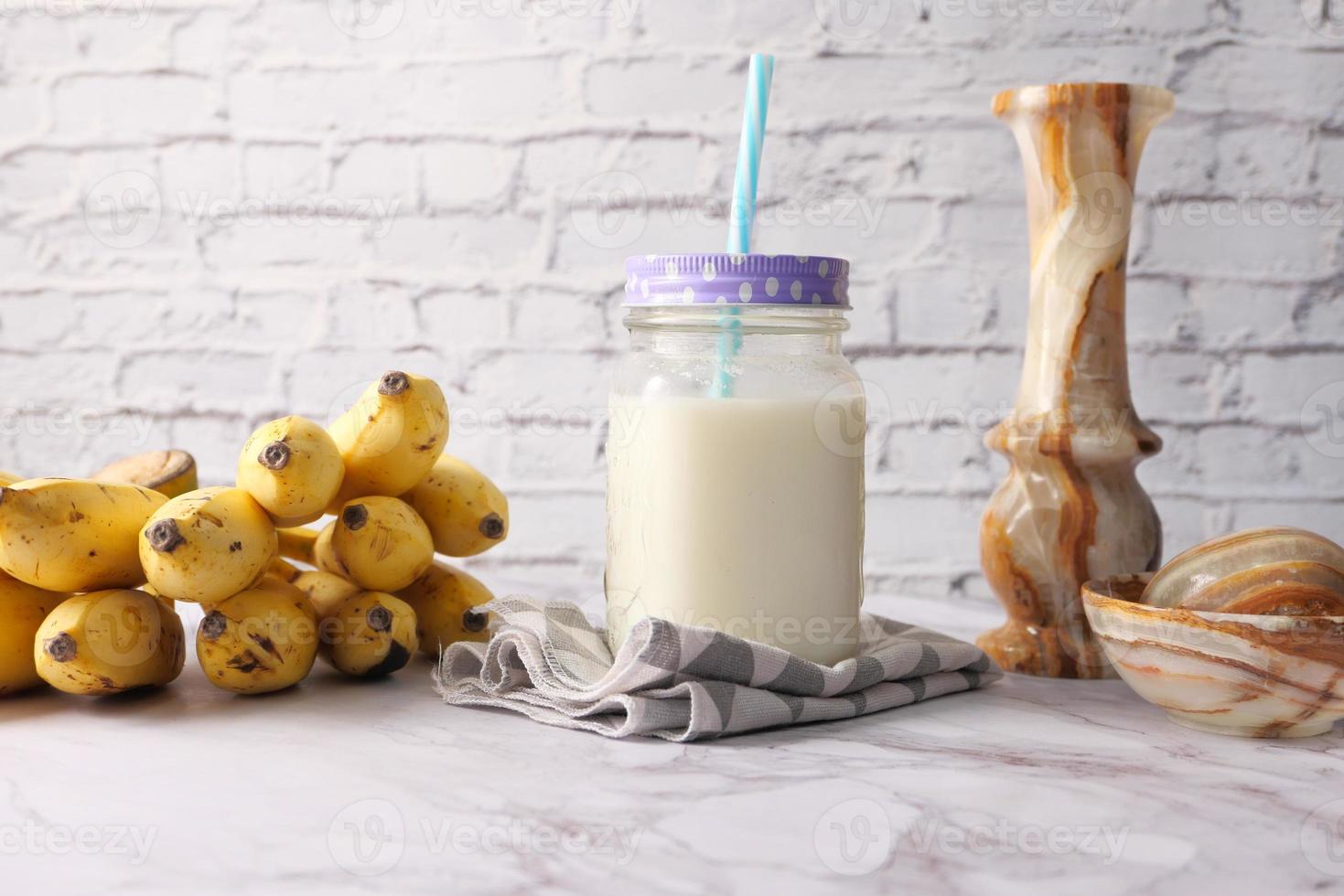 Glass of milk and bananas on table photo
