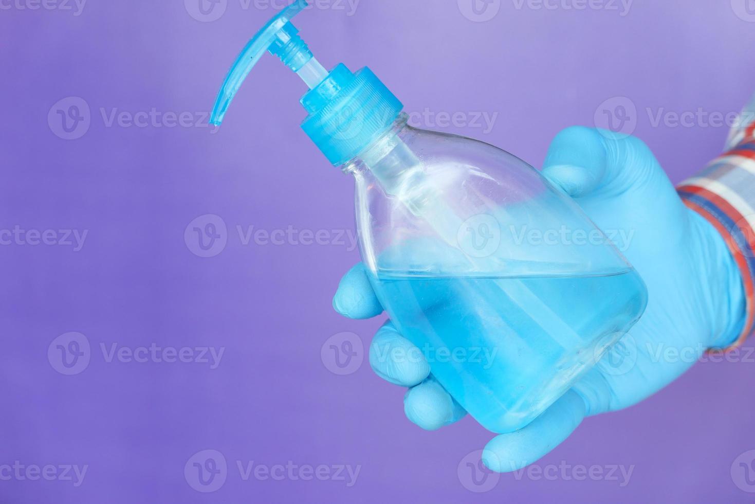 Hand in medical gloves holding sanitizer gel photo