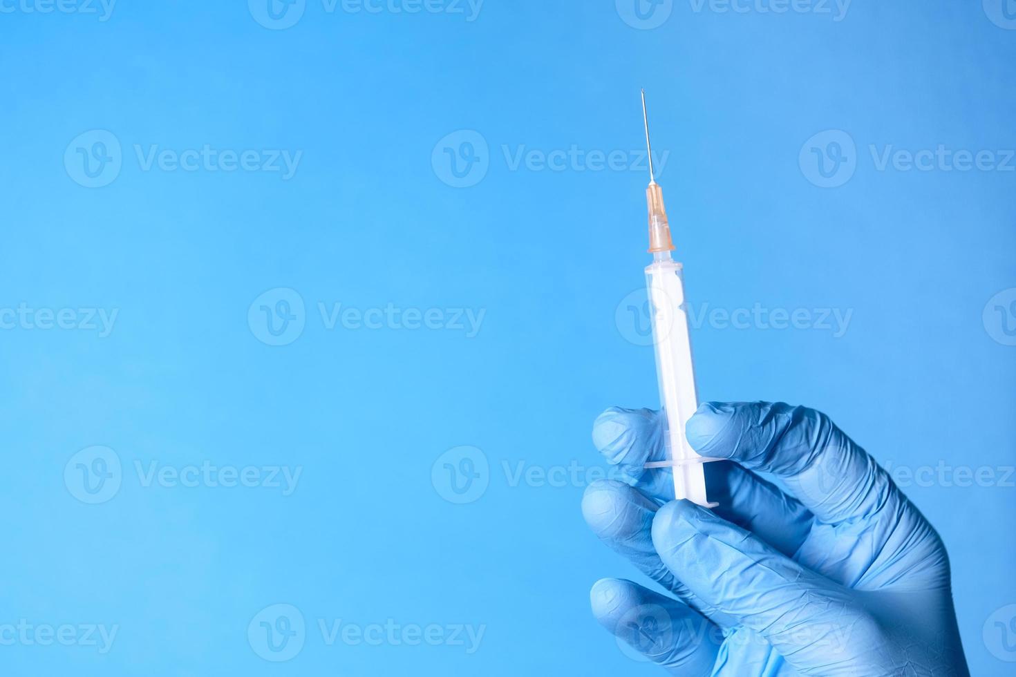 Hand wearing gloves holding syringe photo