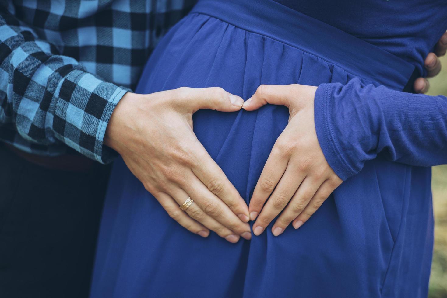 Pareja embarazada con las manos en forma de corazón foto