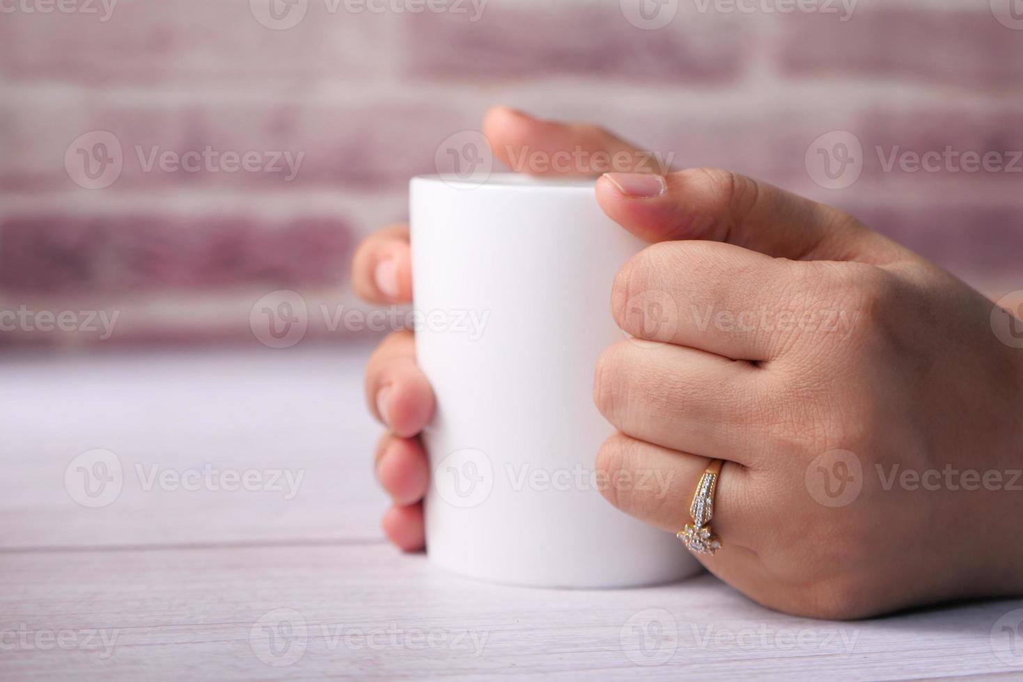 Close up of women's hand holding white color coffee cup photo