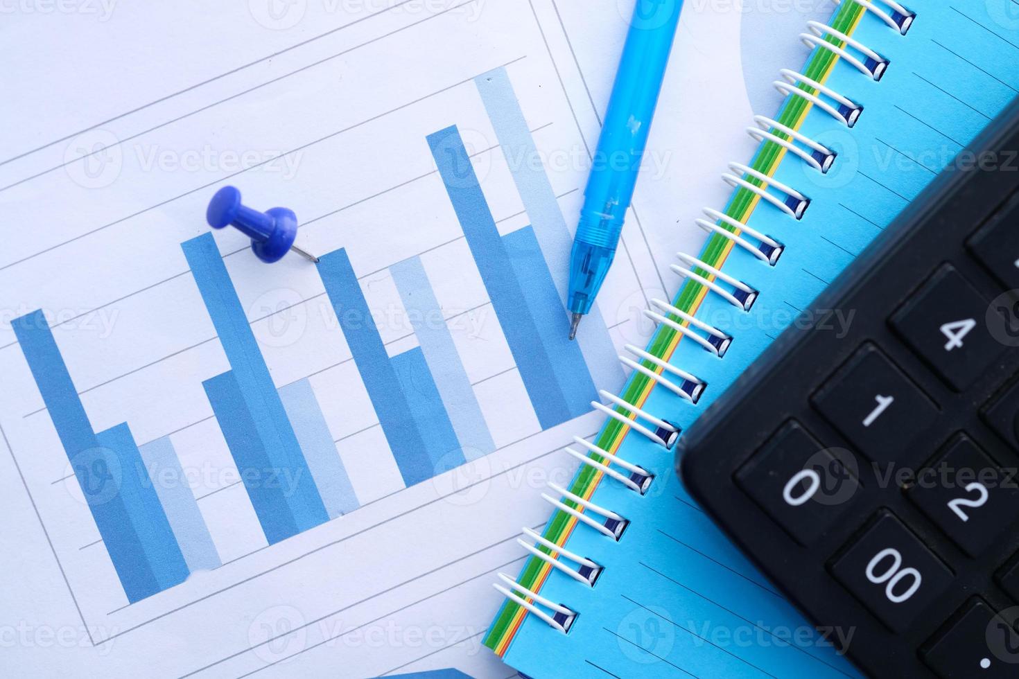 Financial graph, calculator, and notepad on table photo