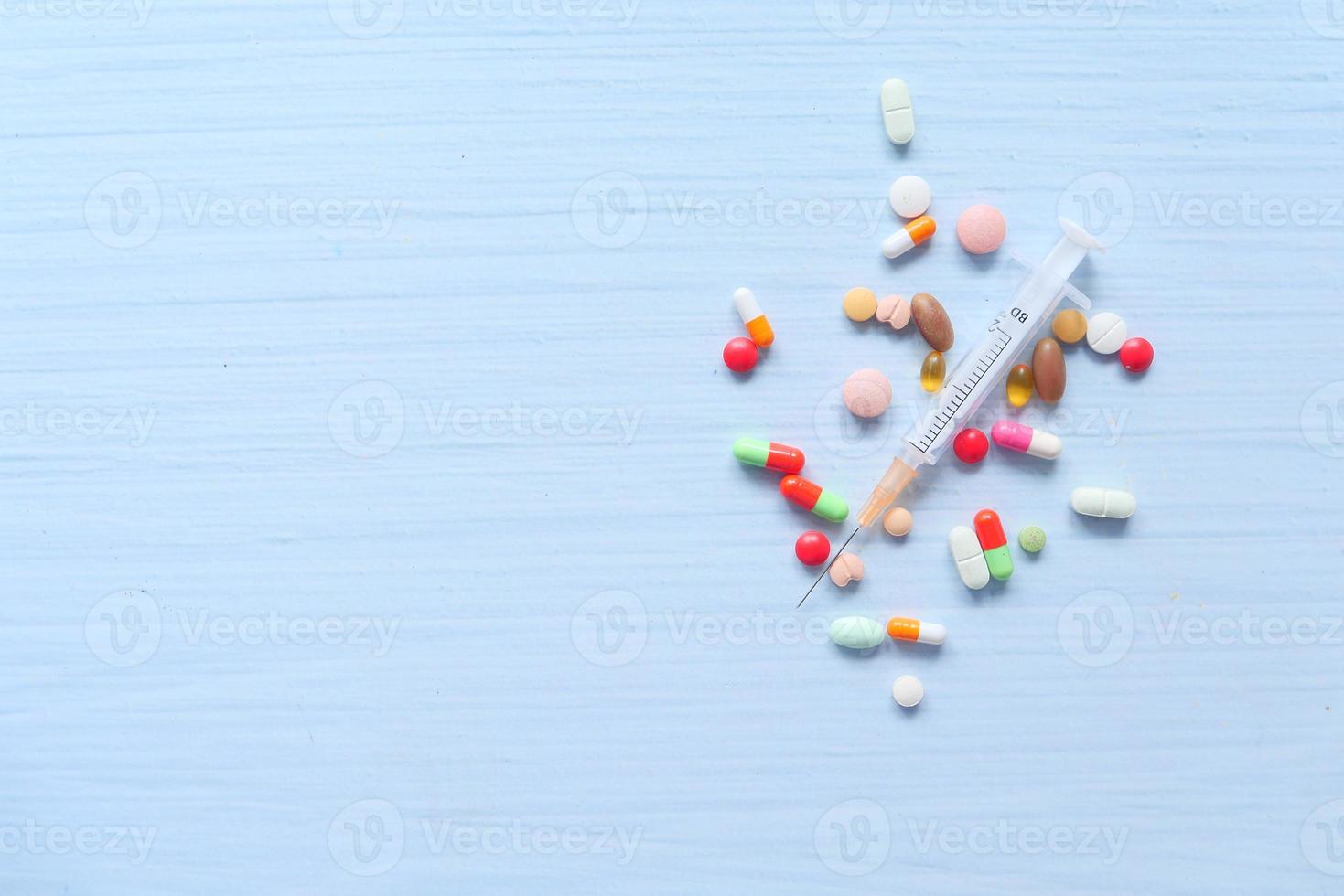 Syringe and pills on white background, top view photo