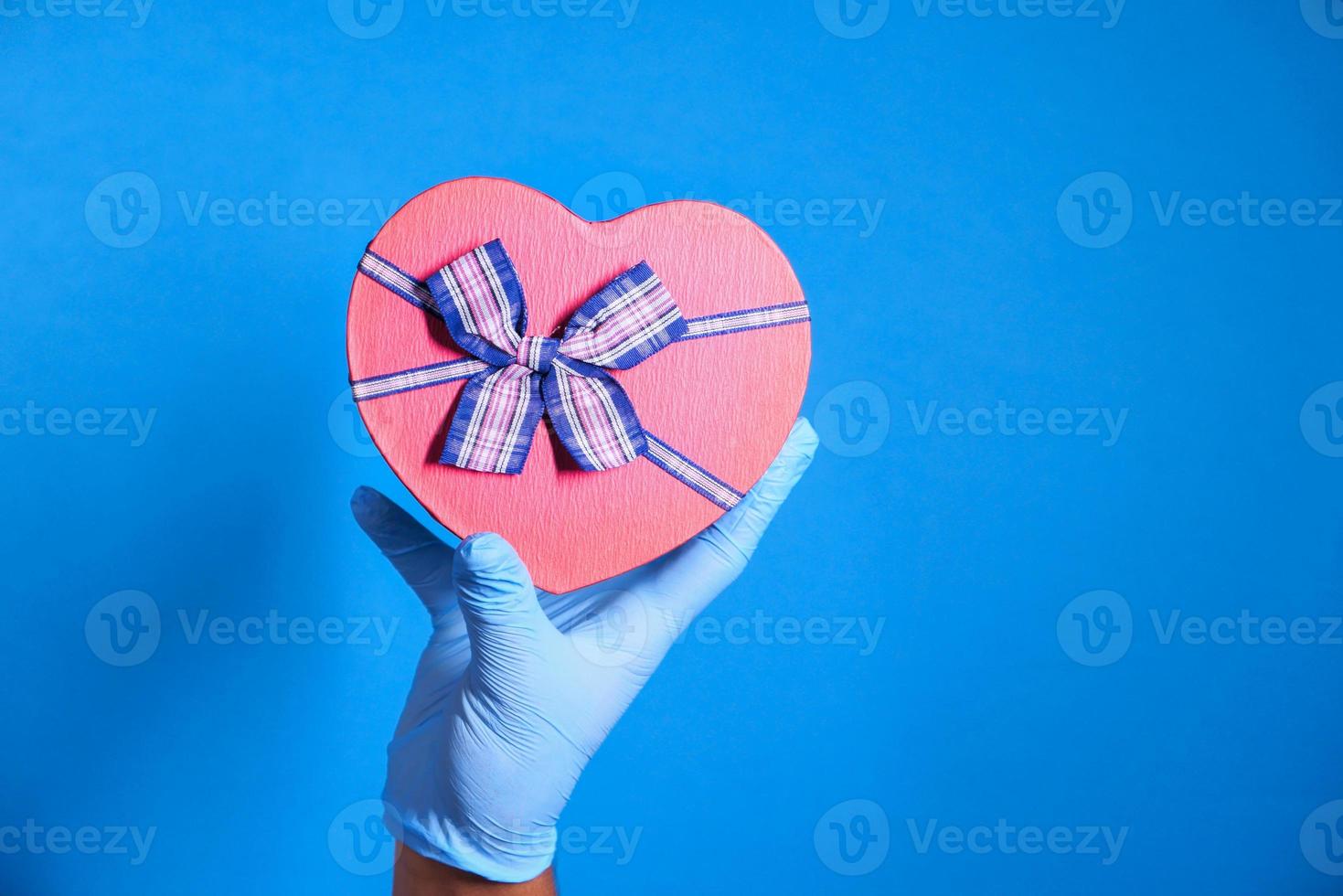 mano en caja de regalo en forma de corazón rojo foto