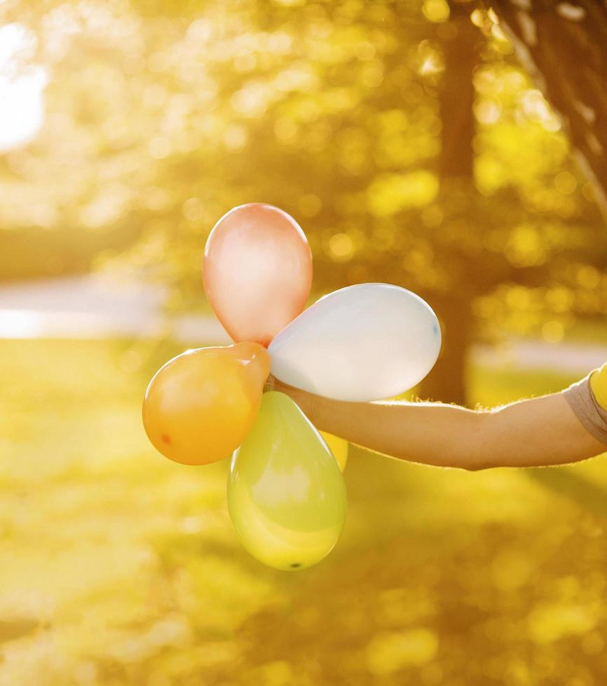 Person holding balloons in sunlight photo