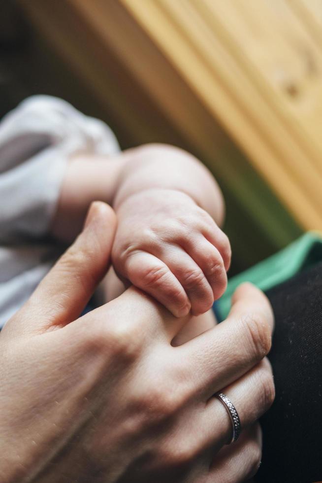 recién nacido agarrando la mano de los padres foto