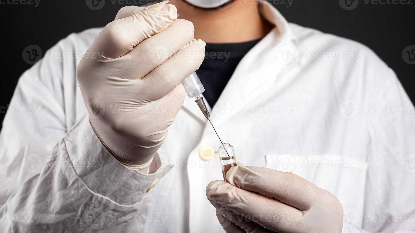 Doctor draws an antibiotic vaccine from an ampoule into a syringe photo