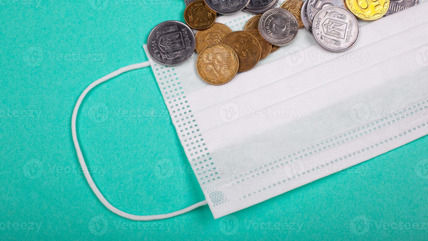 Aumento de los precios de las máscaras médicas, la máscara protectora y un puñado de monedas sobre un fondo azul. foto