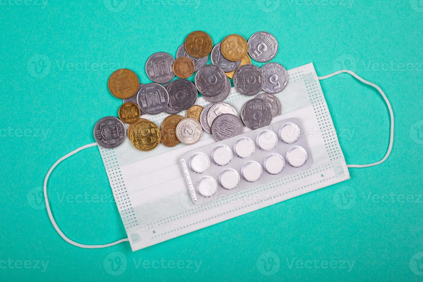 Aumento de los precios de las máscaras médicas, la máscara protectora y un puñado de monedas sobre un fondo azul. foto