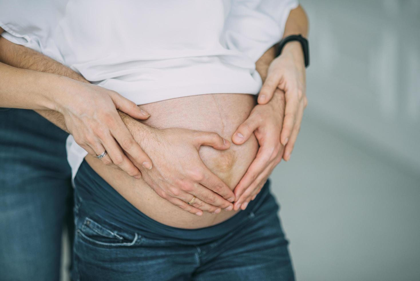 Pregnant couple in white shirts and jeans photo