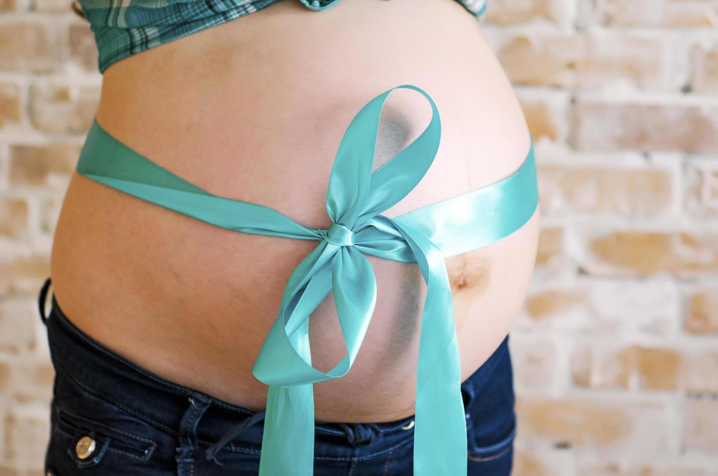 Blue ribbon on pregnant belly photo