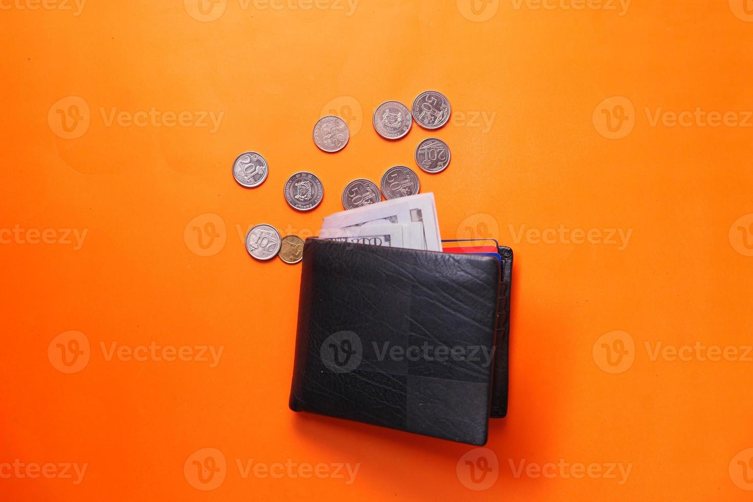 Cash in wallet and coins on orange background photo