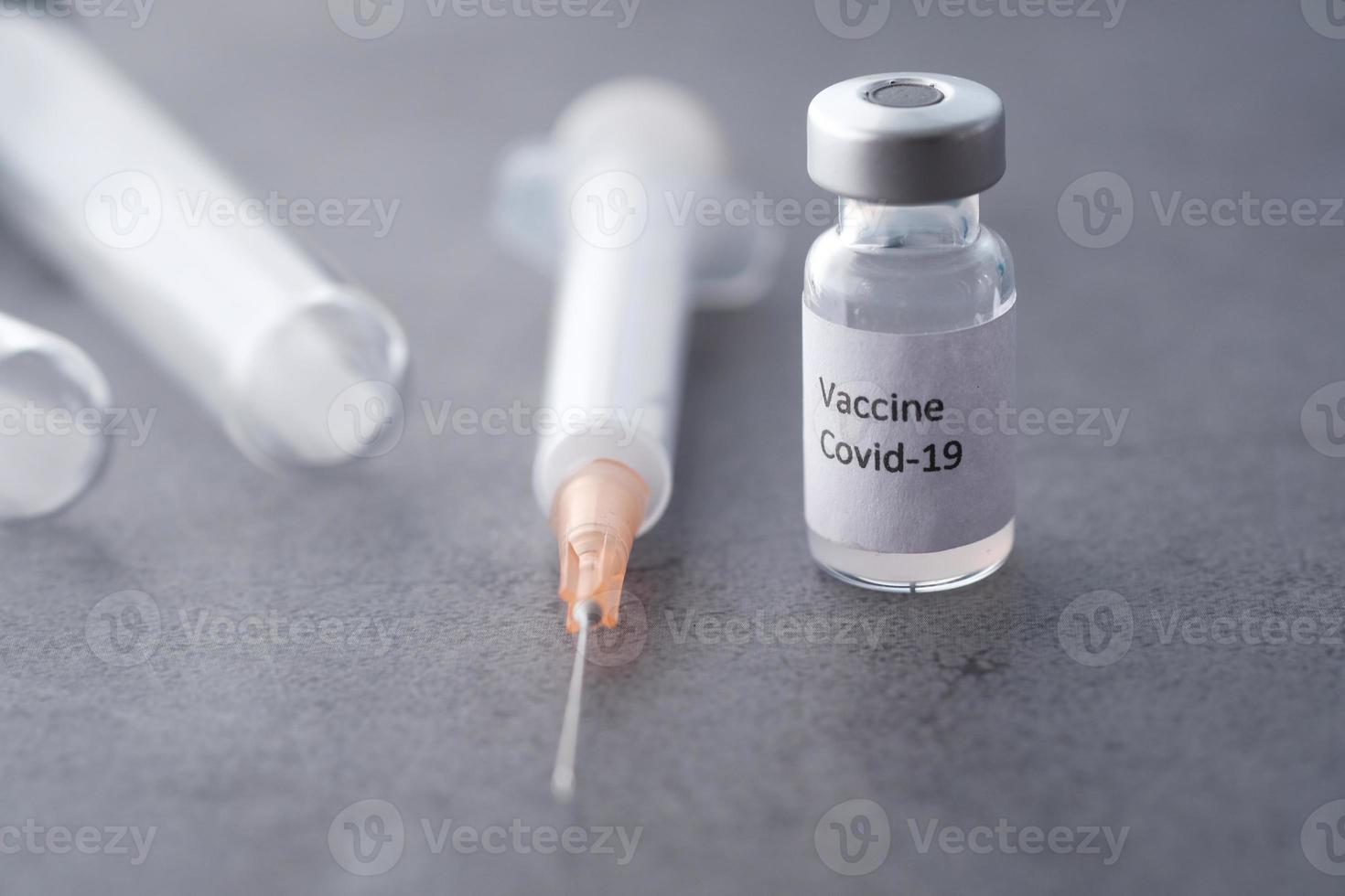 Close up of coronavirus vaccine and syringe on black background photo