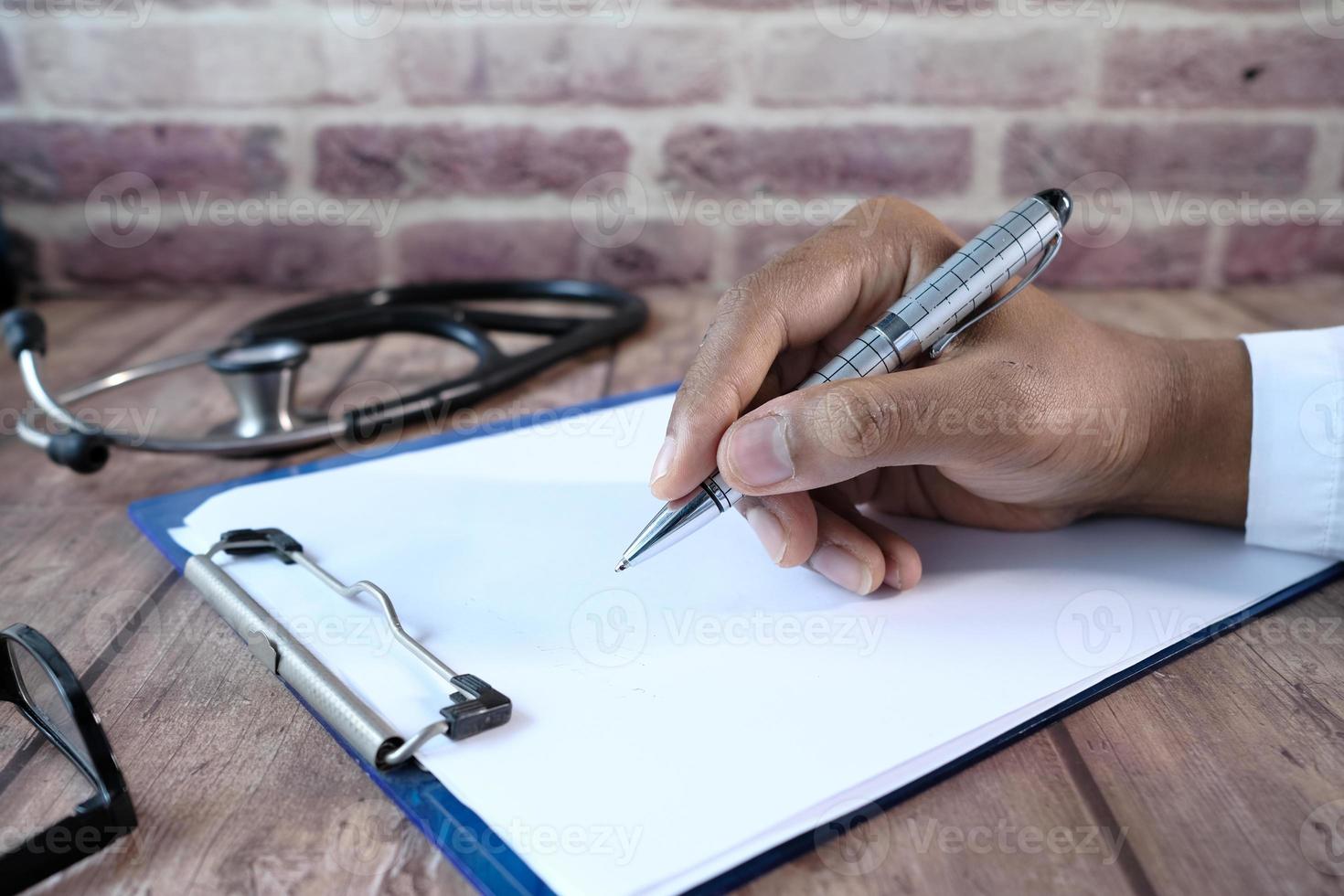 Doctor's hand writing prescription on desk photo