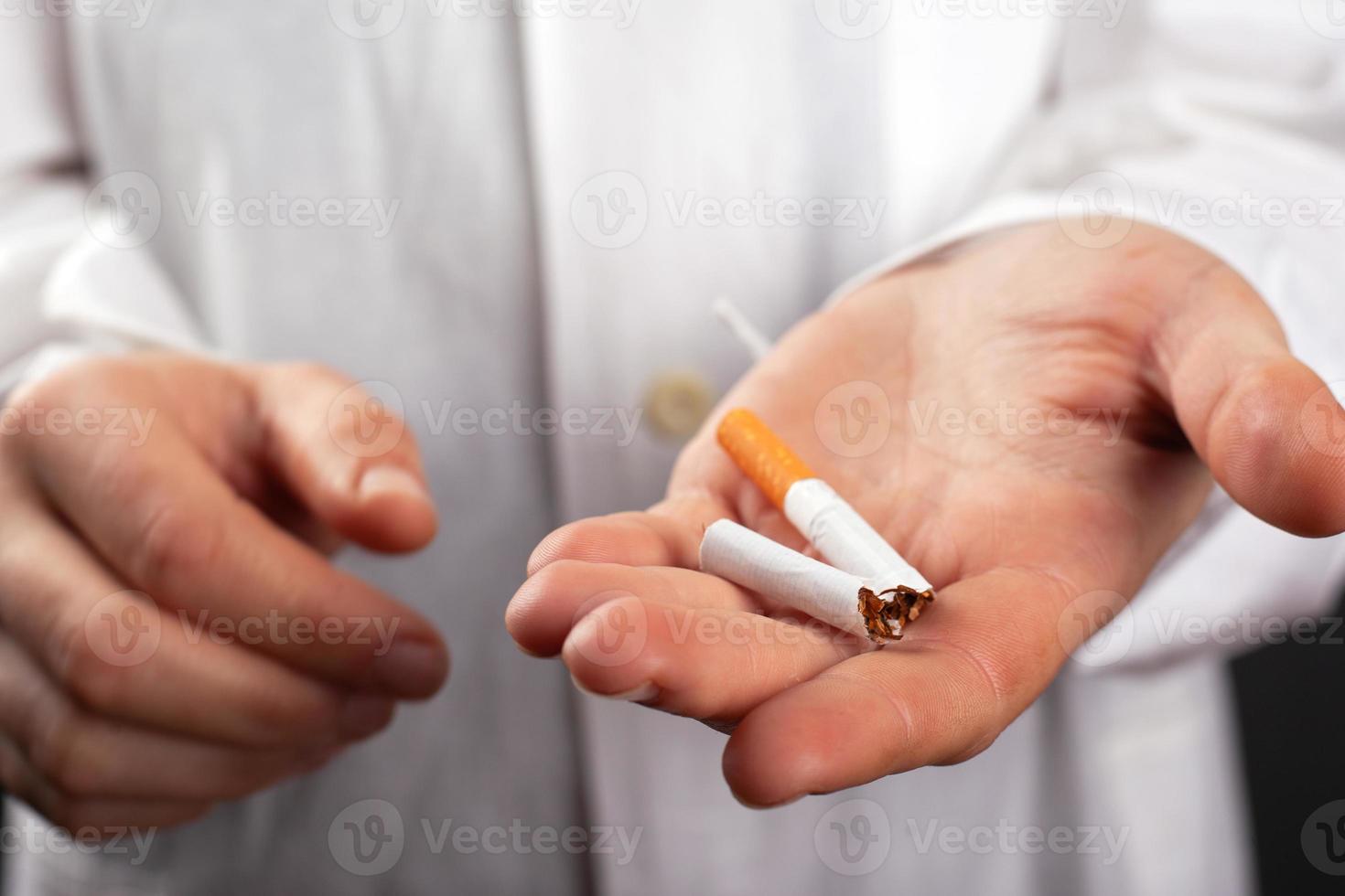 El doctor tiene un cigarrillo roto en la mano. foto