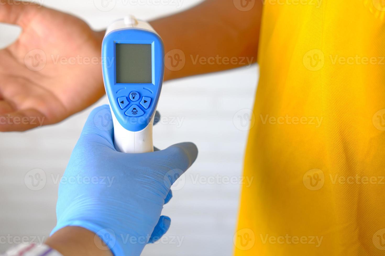 Hand holding infrared thermometer to measure temperature photo