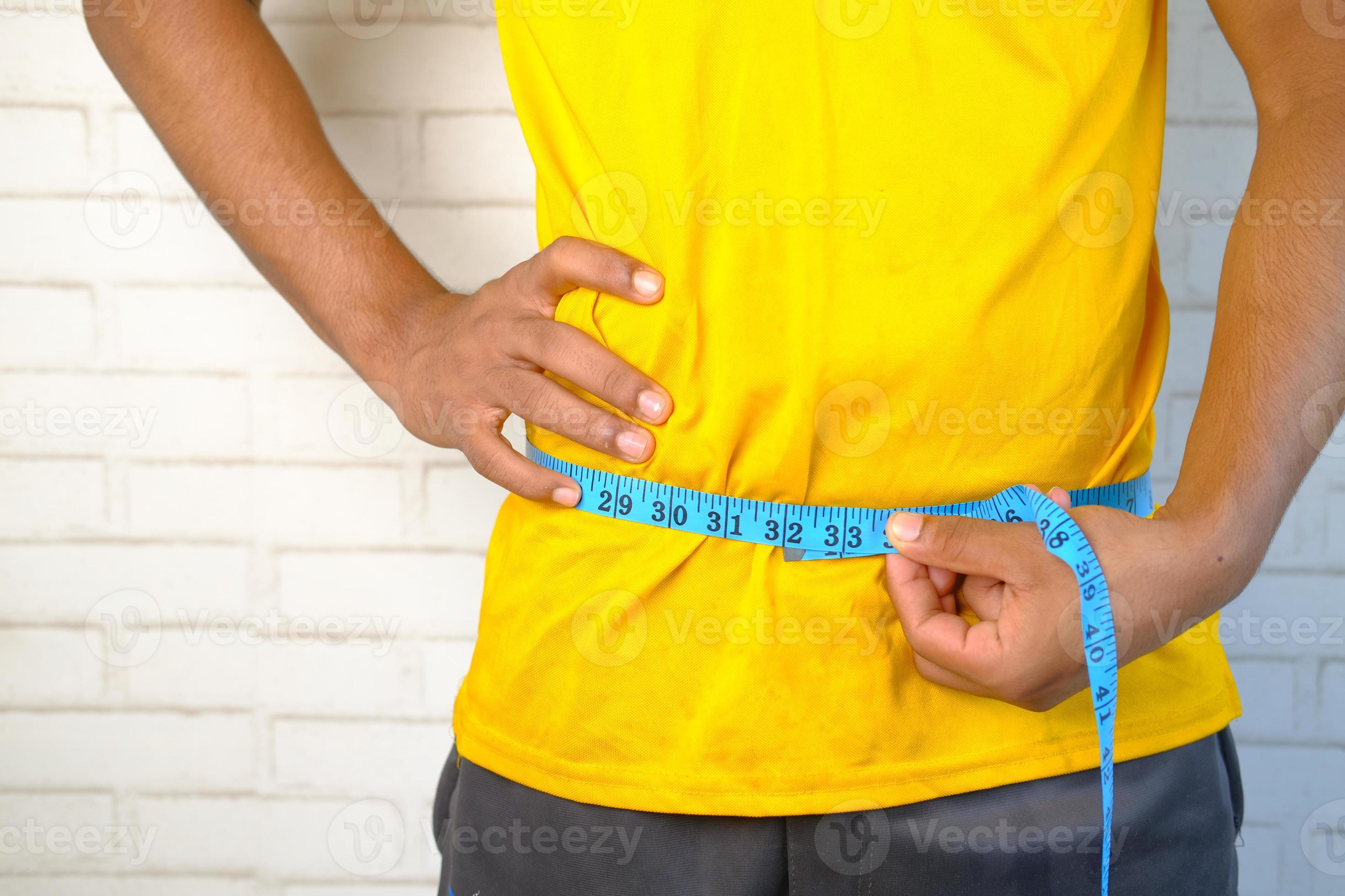 Man measuring his waist with a tape measure 2246454 Stock Photo at