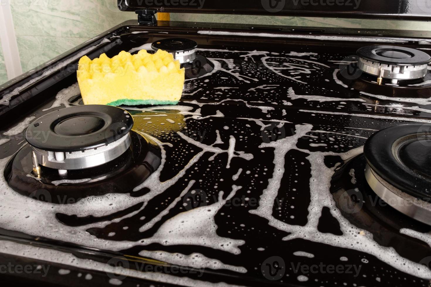 Cleaning the kitchen by washing the surface with foam and a yellow washcloth photo