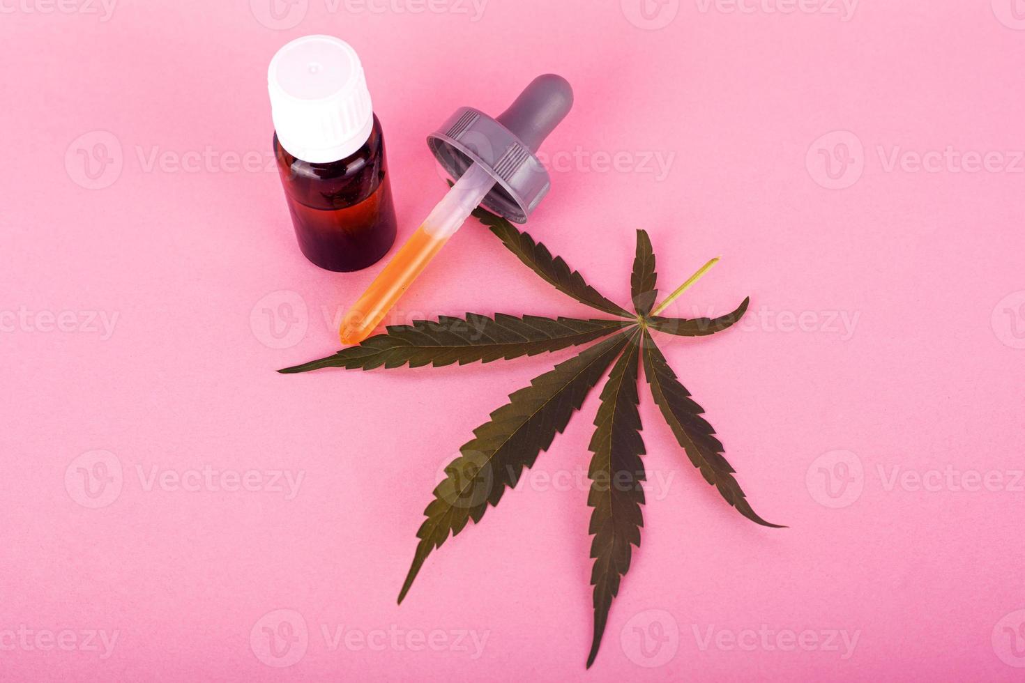 aceite de cáñamo para uso médico, botellas con extracto de cannabis medicinal sobre fondo rosa foto