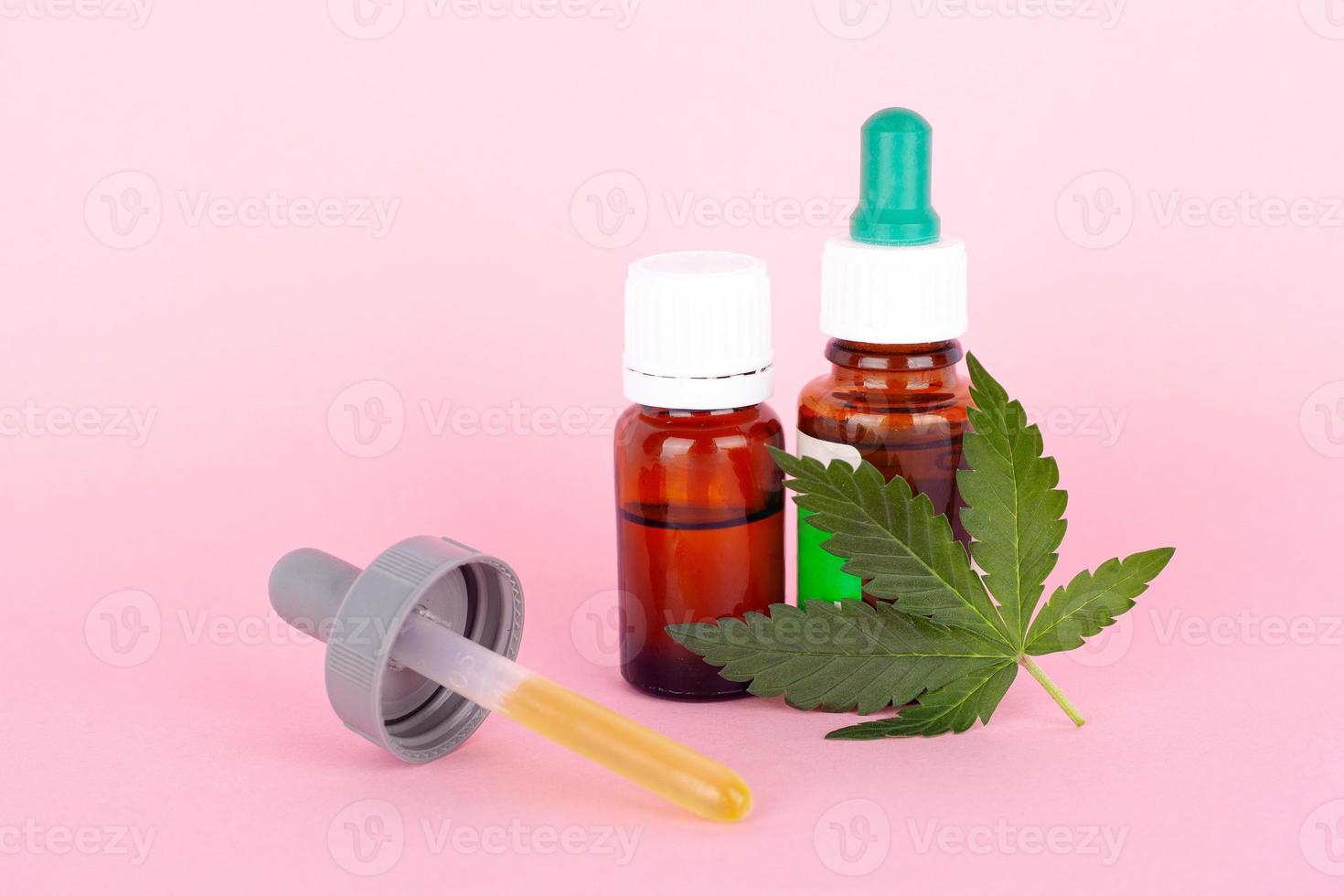 Marijuana extract medications with green leaf and cannabis oil on pink background photo