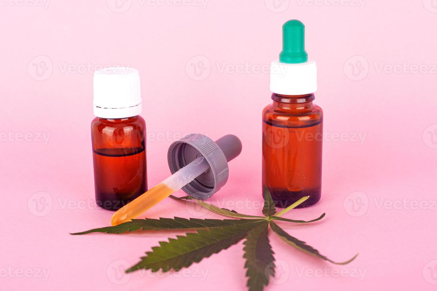 aceite de cáñamo para uso médico, botellas con extracto de cannabis medicinal sobre fondo rosa foto