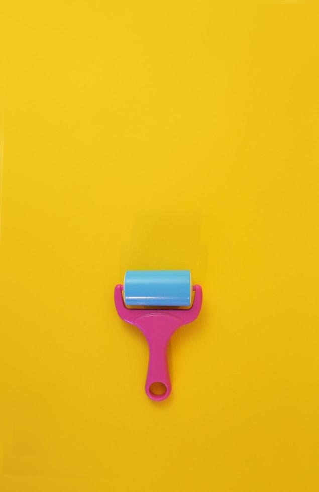 Paint roller against clean yellow background with copy space for text message. Conceptual image. photo