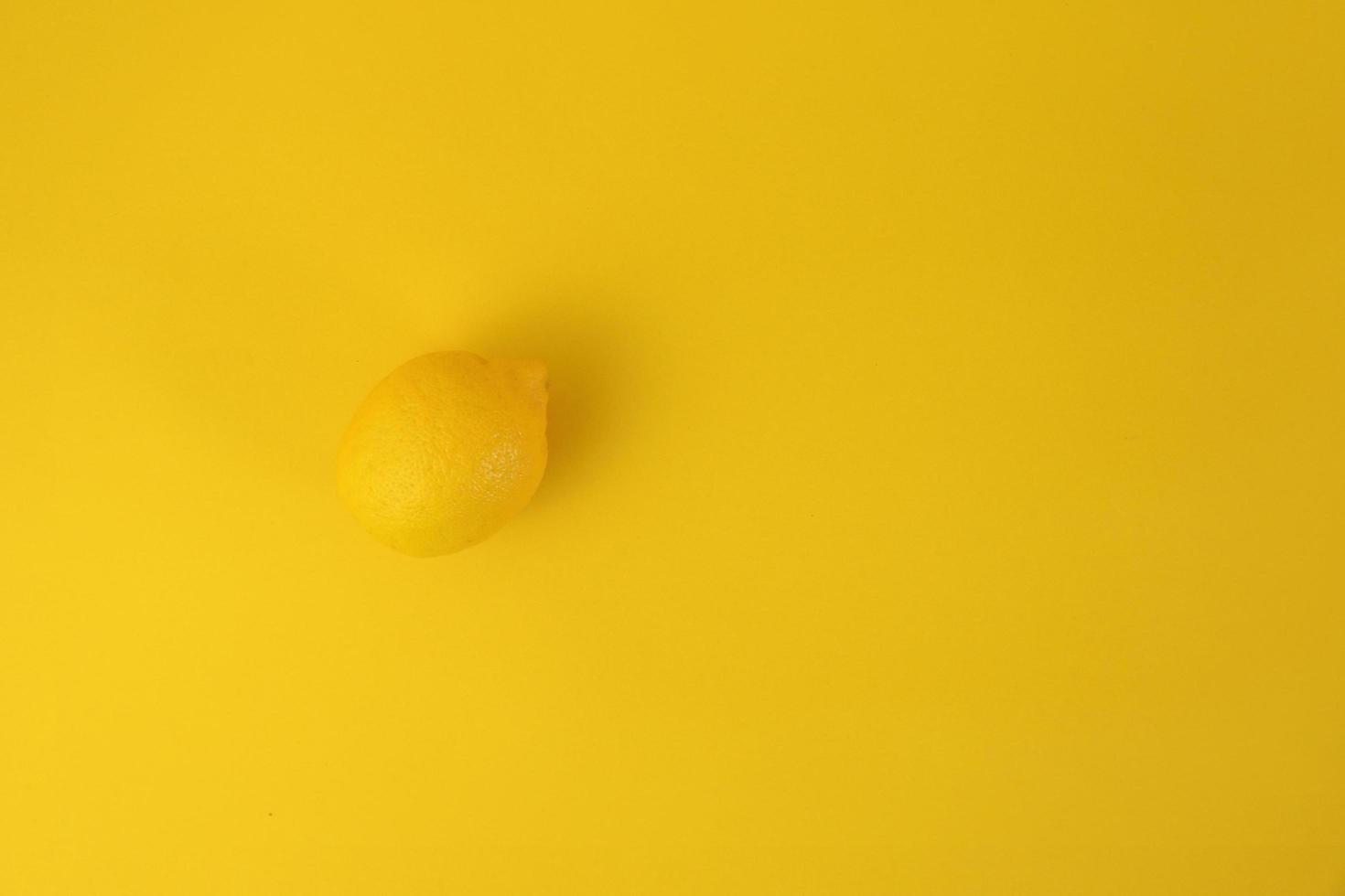 Yellow lemon isolated on clean yellow background. Abstract minimal concept. photo