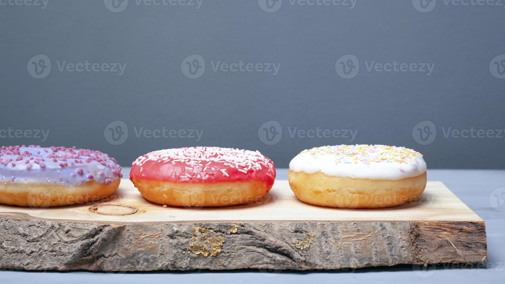 Multicolored assorted red, white and violet donuts coated with glaze and sprinkled with Easter powder on a wooden stand photo