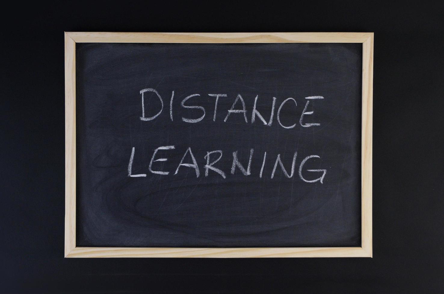 Hand-drawn title Distance Learning on a black chalkboard with wooden frame. photo