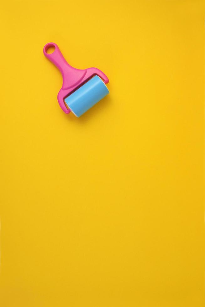 Paint roller against clean yellow background with copy space for text. photo