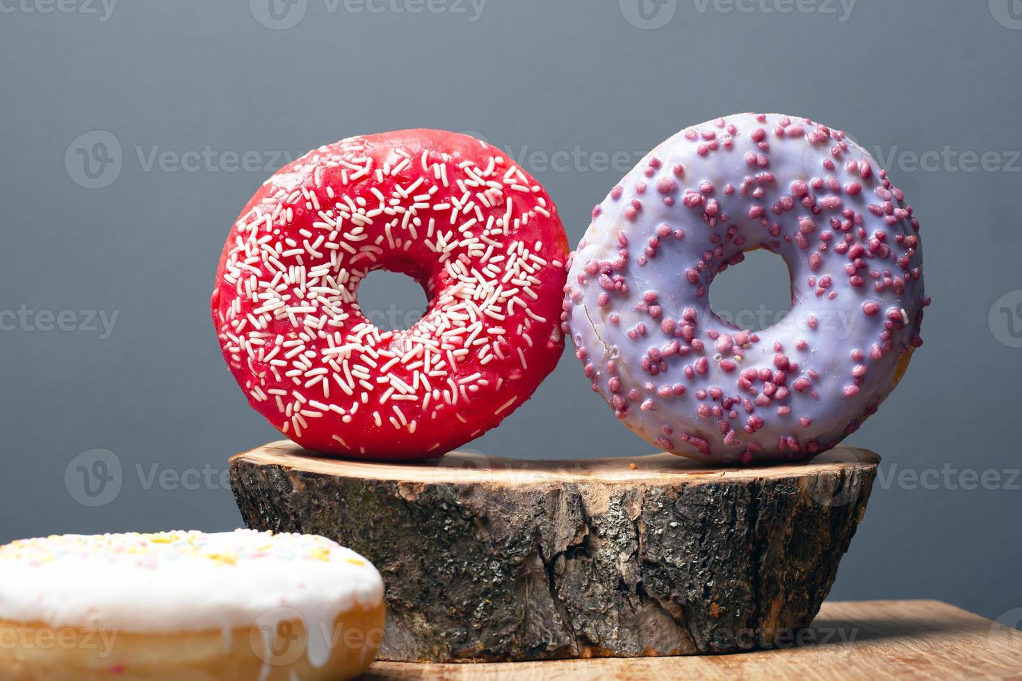 Donuts de dos colores en primer plano de tocón de madera foto