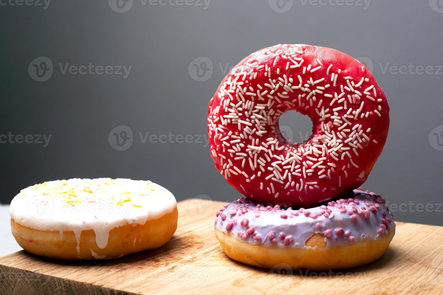 Multicolored holiday donuts powdered on a wooden stand on a gray background photo
