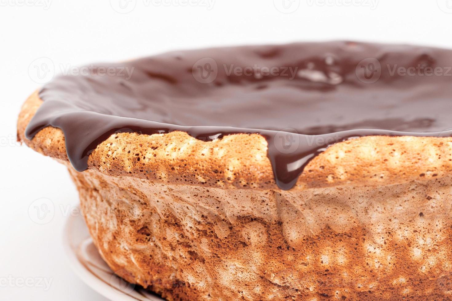 Chocolate que fluye a los lados del pastel sobre fondo blanco. foto