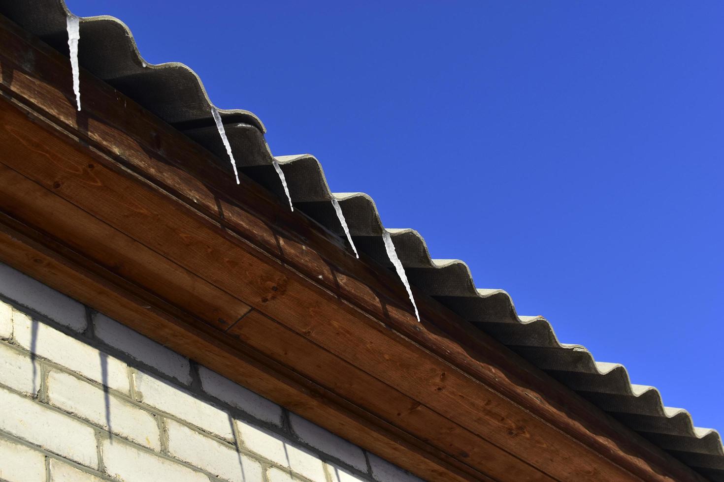 Ice icicles on the roof of the house in winter photo