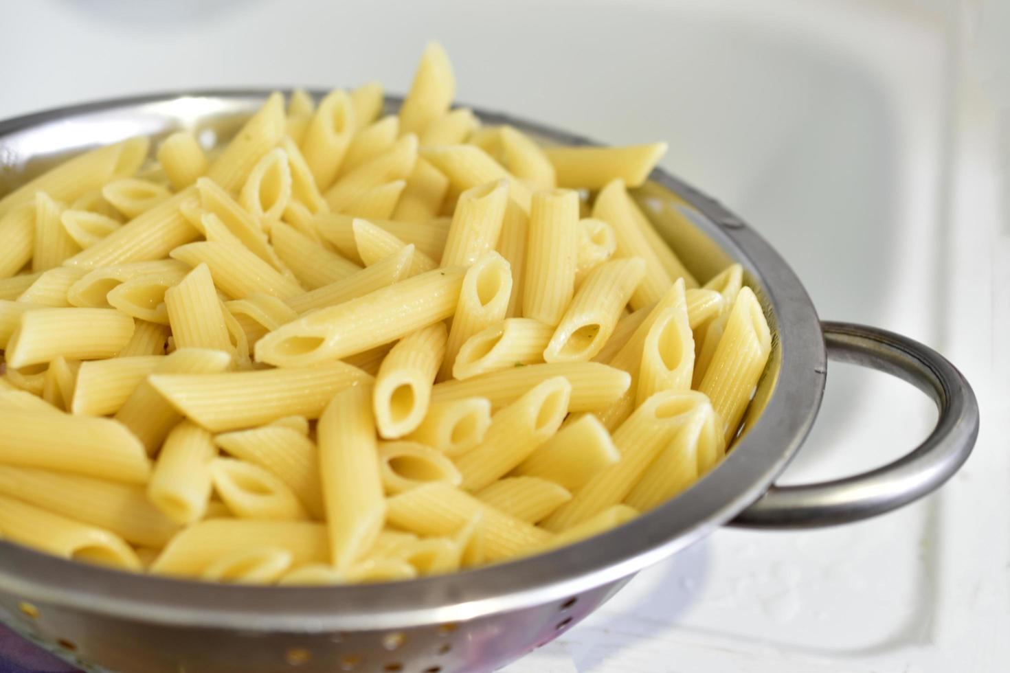 Pasta italiana recién lavada en un colador en la cocina foto